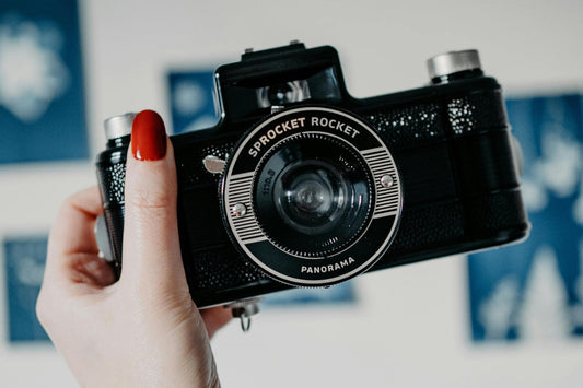 a person holding a camera choosing between using analog and digital cameras, 
