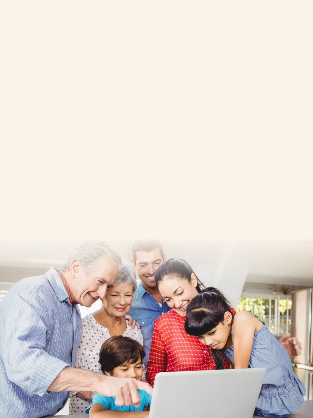 A multigenerational family, including grandparents, parents, and children, gathered around a laptop, smiling and looking at the screen.
