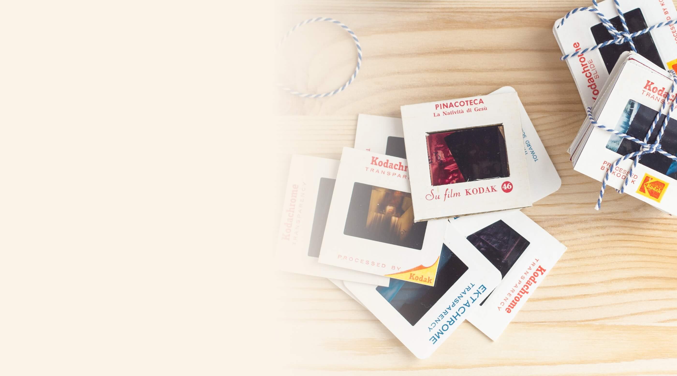 Vintage Kodak slides and slide boxes stacked with string on a wooden surface