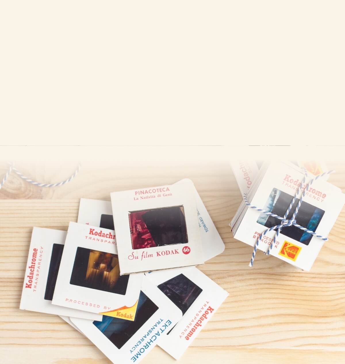 Vintage Kodak slide boxes tied with string, surrounded by Kodak slide frames on a wooden surface
